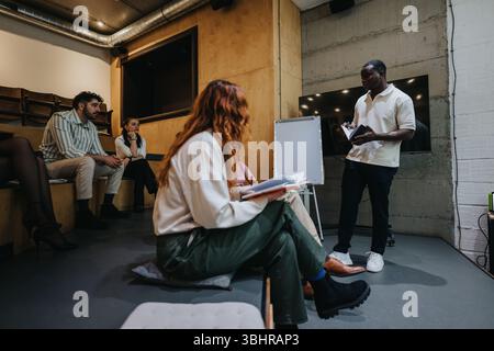 Creative team collaborating during a seminar with a speaker presenting ideas in a modern workspace Stock Photo