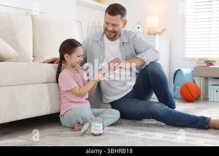 Father giving his daughter pocket money at home Stock Photo