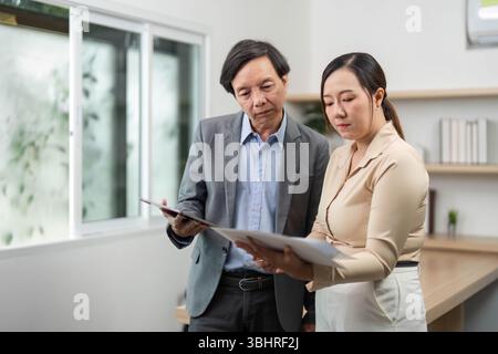 Business Collaboration and Professional Discussion. Two colleagues reviewing documents in a modern office. Stock Photo