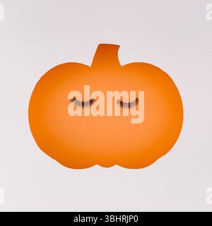Autumn pumpkin cutout with false eyelashes. Minimal fall beauty concept. Creative seasonal beauty and makeup art. Trendy fall aesthetic. Flat lay styl Stock Photo