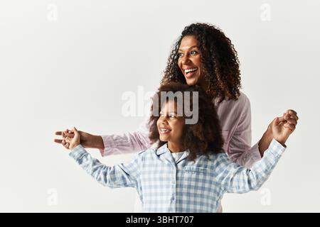 Smiling Black mother and daughter in PJs holding hands. Stock Photo