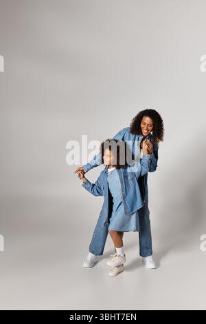 Black mom and daughter in denim clothes, holding hands. Stock Photo