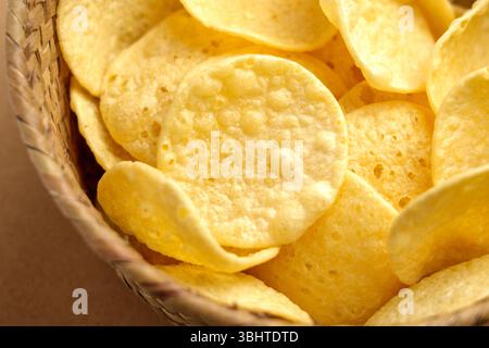 Crispy potato chips in rustic wicker bowl. Junk food snack. Close-up Stock Photo