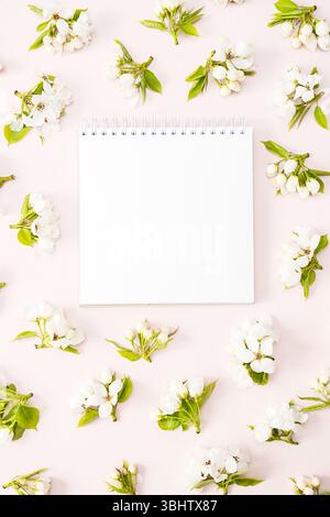 Empty Notebook in Center Framed by White Pear Blossoms on Pink Background. Springtime concept. Stock Photo