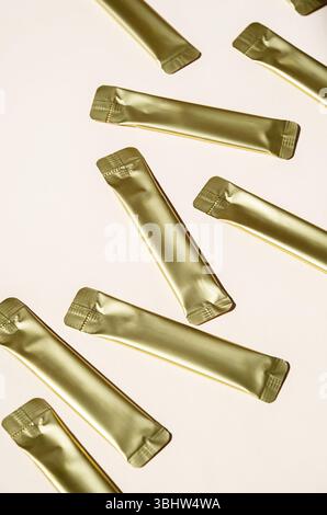 Golden Metallic Stick Packaging on Light Background. Small Packets for Food, Medicine or Cosmetic Product. Stock Photo