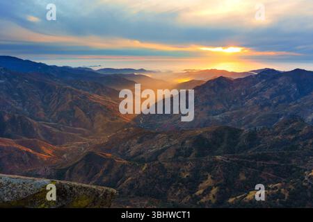 Breathtaking view of sunset casting golden light over the mountainous valleys of Sequoia National Park, showcasing dramatic terrain and colorful sky. Stock Photo