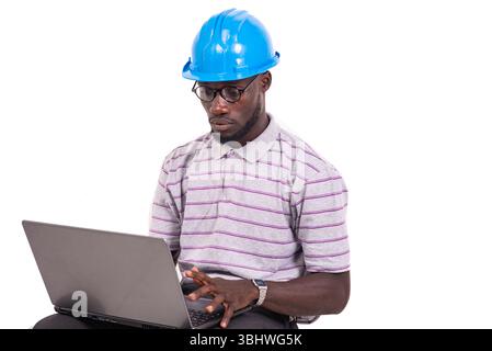 young man engineer wearing safety helmet sitting on chair and working with laptop. Stock Photo