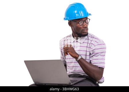 young man engineer wearing safety helmet sitting on chair and working with laptop. Stock Photo