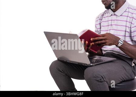 young man sitting on chair and checking notes in notebook using laptop. Stock Photo