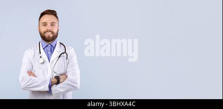 Portrait of positive male doctor posing with crossed arms and smiling at camera over grey studio background Stock Photo