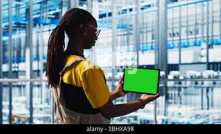 Smart factory specialist using mockup laptop to test automated systems and ensure reliability. Woman uses isolated screen notebook to identify bottlenecks and optimize equipment, camera A Stock Photo
