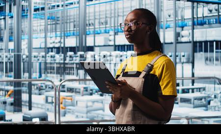 Smart factory engineer implements automated workflows and control systems using tablet, computerizing manual operations. Industry 4.0 worker integrates sensors into production using device, camera A Stock Photo