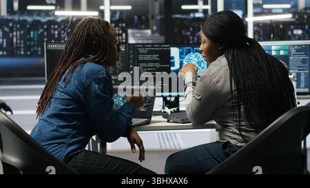 Data center coworkers doing brainstorming, using artificial intelligence machine learning models to configure equipment. IT experts cooperating in server farm, working on optimizing systems, camera B Stock Photo