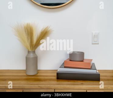 Stack of blank books, candle, and ceramic vase with faux pampas grass on wood table with copy space interior template Stock Photo
