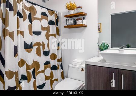 Modern bathroom in white and brown, designer shower curtain, and wood cabinet sink and toilet Stock Photo