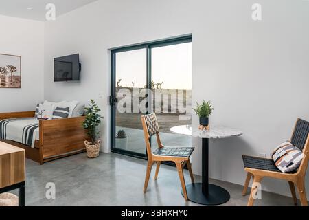 Modern desert living room interior of concrete floors with sofa and dining table set with woven chairs Stock Photo