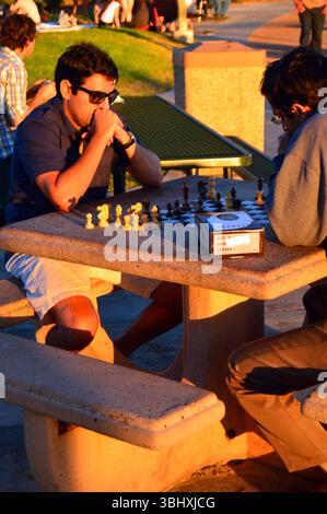 Two friends engage in a compelling chess game in a park near the shore in Laguna Beach, California Stock Photo