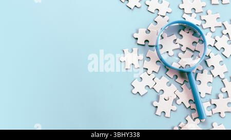 Magnifying Glass Over Jigsaw Puzzle Pieces for Detailed Inspection Stock Photo
