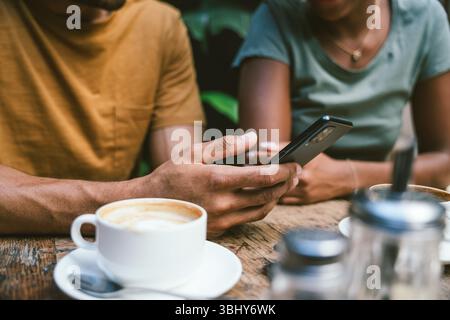 Closeup of couple using smartphone sitting in coffee shop Stock Photo