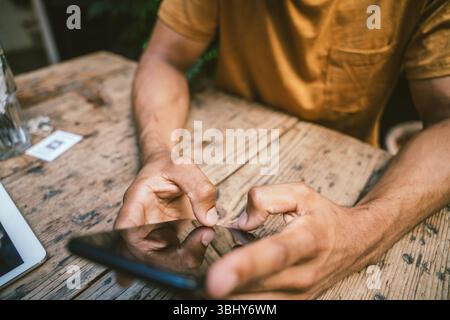 Closeup of man using smartphone while sitting at table in coffee shop Stock Photo
