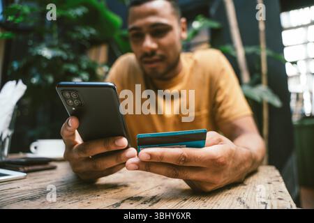 Man making online payment using smartphone and credit card in coffee shop Stock Photo