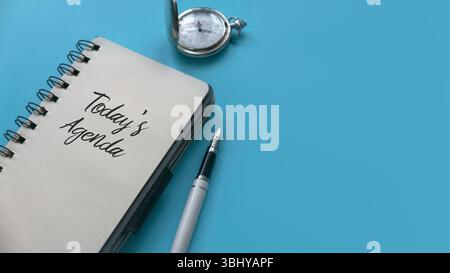 Top view of pen and notebook written with Today's Agenda on blue background with copy space Stock Photo