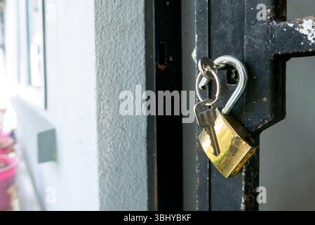 Golden Padlock with Keys Hanging on Dark Door - Security Detail with White Textured Wall Background Stock Photo
