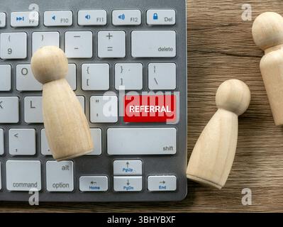 Referral Button Keyboard with Wooden People Figures Stock Photo