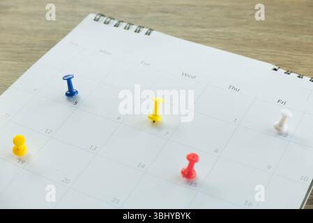 Colorful Push Pins on a Spiral-Bound Calendar Page for Planning and Organization Stock Photo