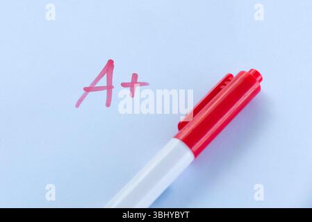 A+ Grade on Exam Paper with Red Pen on White Background Stock Photo