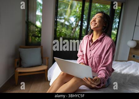 Asian woman using her laptop for remote freelance work, the freedom of a digital nomad lifestyle Stock Photo