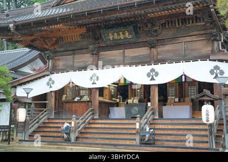 On May 17, 2025, at Motozenkoji Temple in Iida City, Nagano Prefecture, gentle rain falls quietly on the old stone steps, wetting umbrellas held by vi Stock Photo