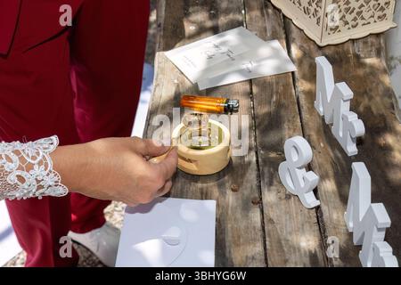 Creative wedding detail of the vow cards, ring, and wax seal stamp prepared on a rustic wooden table, capturing the love-filled ambiance. Stock Photo