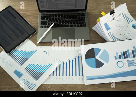 A report document image shows workspace with various financial charts, graphs, laptop, and tablet, indicating data analysis or business planning Stock Photo