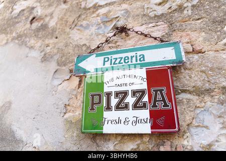 Vintage pizzeria sign with Italian flag colors hanging on an old stone wall in Italy. High quality photo Stock Photo