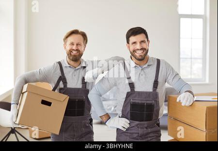 Happy men from delivery service, posing with cardboard boxes, providing moving service Stock Photo