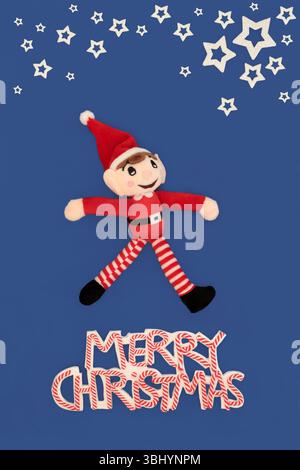 Merry Christmas sign, elf soft toy, white stars on blue background. Festive playful whimsical cheerful concept abstract design for holiday season. Stock Photo