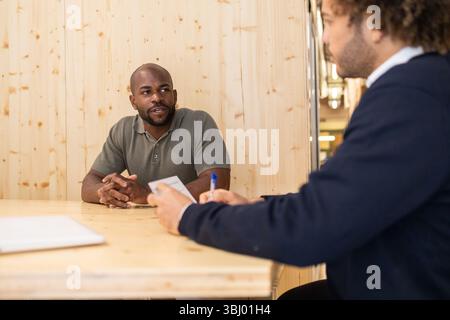 A casual meeting unfolds in a stylish Barcelona coworking space. Two professionals engage in a lively discussion, enhancing productivity and collabora Stock Photo