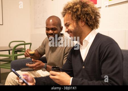 Two professionals enjoy a casual coffee break in a stylish coworking space in Barcelona. This modern office setting fosters creativity, collaboration, Stock Photo