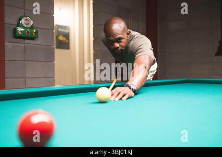 A man intently focuses on a shot while playing pool in a modern coworking space, where innovation meets recreation. The setting combines work and leis Stock Photo