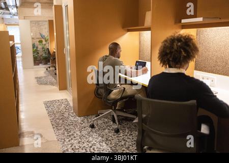A modern coworking space in Barcelona featuring individuals focused on their laptops, highlighting a productive and collaborative environment with sty Stock Photo