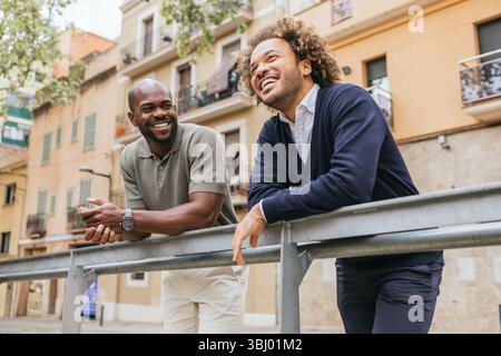 Two colleagues share a light moment outside their office in a charming Barcelona street, showcasing the vibrant and collaborative spirit of modern cow Stock Photo