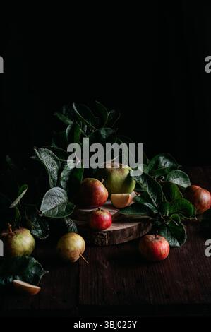 A rustic display of apples surrounded by lush green leaves on a wooden table. The vibrant colors and natural textures highlight the freshness and appe Stock Photo