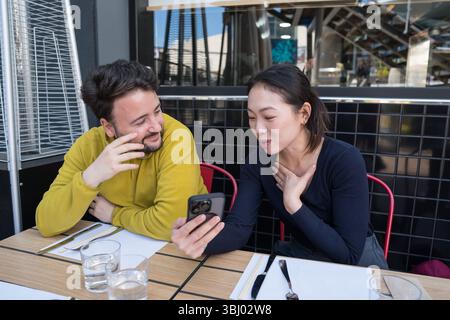 Two friends enjoy a delightful meal at an Asian restaurant, engaging in lively conversation and sharing moments. The ambiance is modern, reflecting a Stock Photo