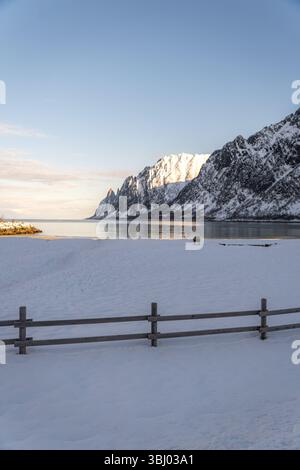 Scenic winter landscape in Ersfjord, Norway, featuring a snow-covered beach and majestic mountains. A serene mix of natural beauty and tranquility by Stock Photo
