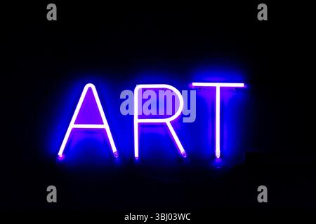 Lit up blue neon sign displaying the word 'ART' glowing brightly against a dark background Stock Photo
