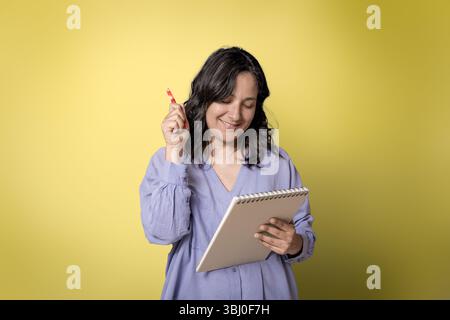 young adult woman in her 40s taking notes on notebook with pen. Stock Photo