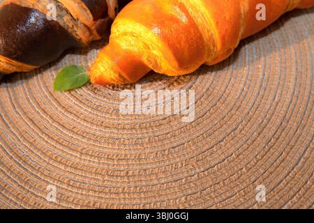 Two fresh croissants, one classic golden and the other dark chocolate, lie on a decorative woven mat. Ideal for breakfast or dessert in a cozy setting Stock Photo