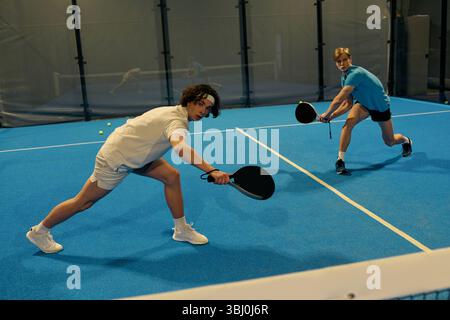 Two young sportsmen showcase their skills while playing an exciting game of padel. Stock Photo