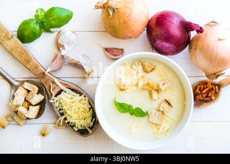 onion soup puree in a white plate with vegetables on the table Stock Photo